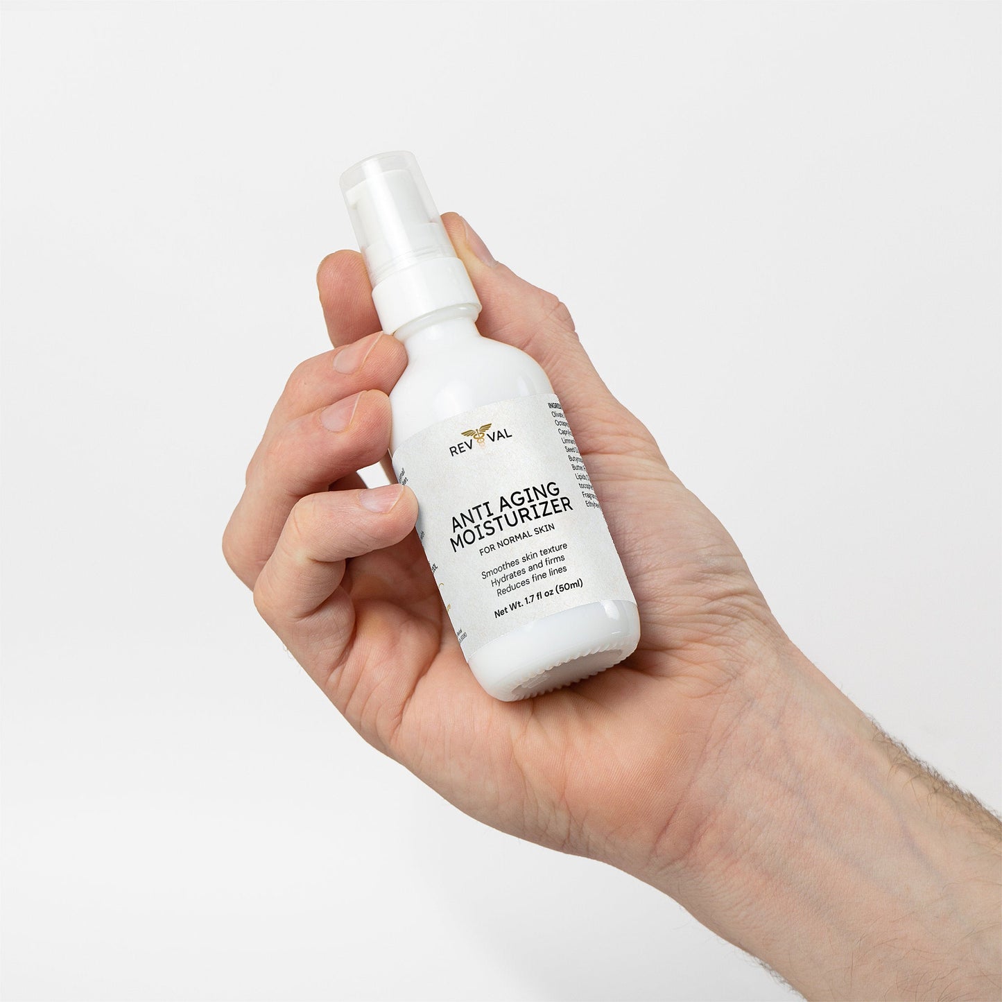 Hand holding a bottle of RevivaL Anti Aging Moisturizer against a white background