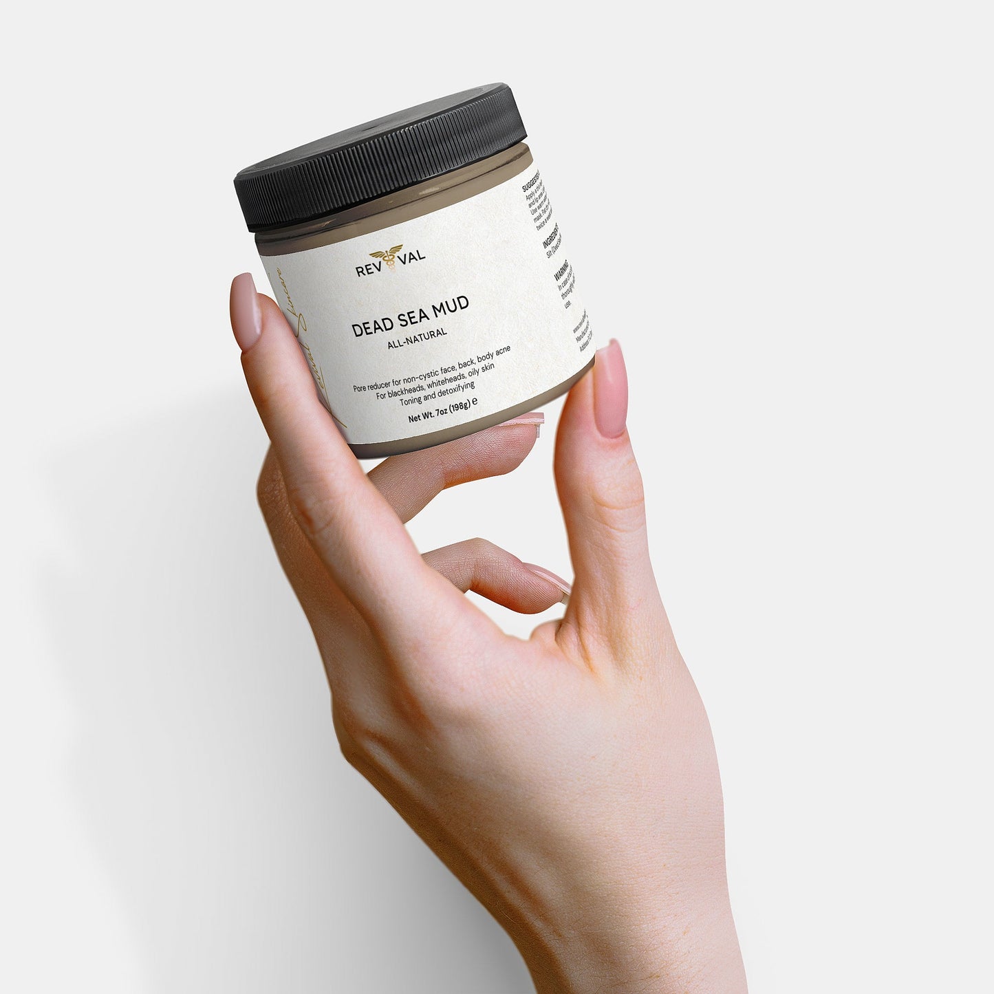 Hand holding a jar of Rev Val Dead Sea Mud on a light background