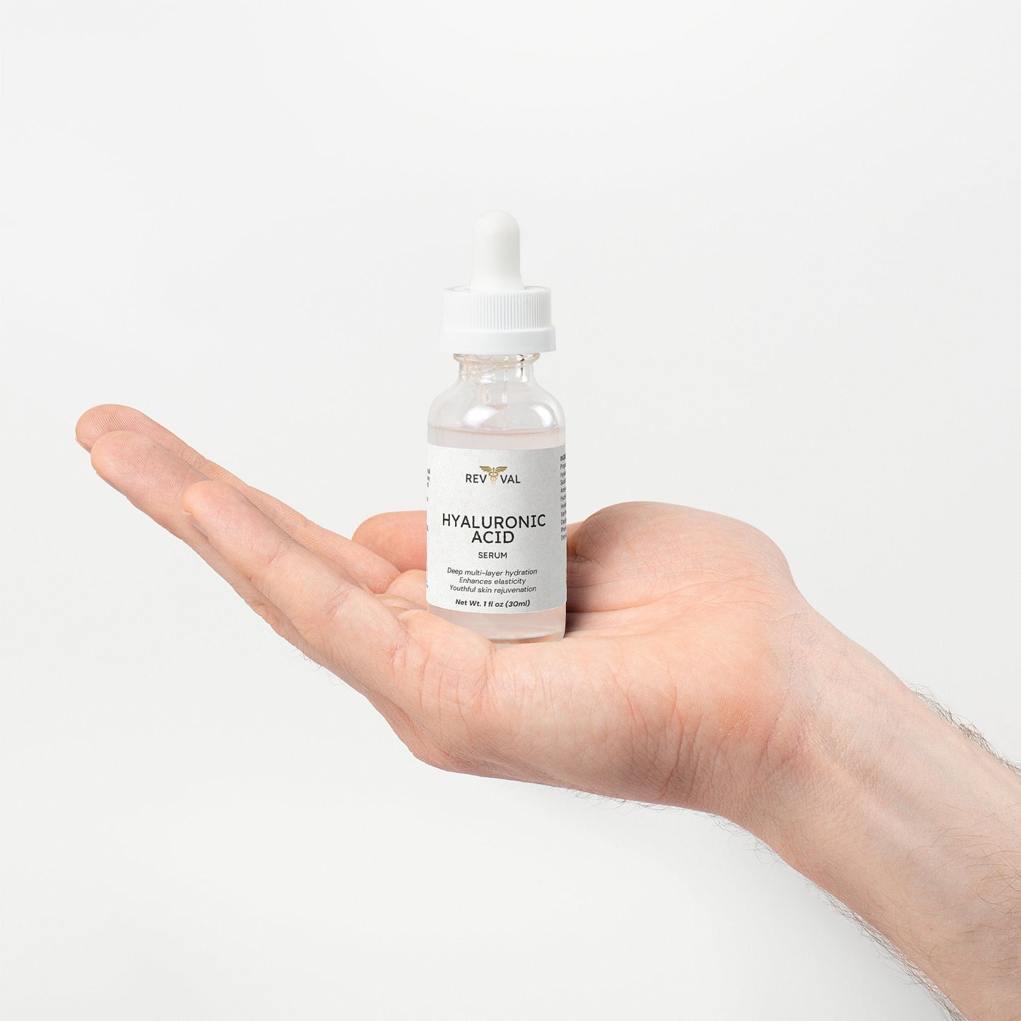 Hand holding a bottle of RevivaL Hyaluronic Acid Serum against a white background
