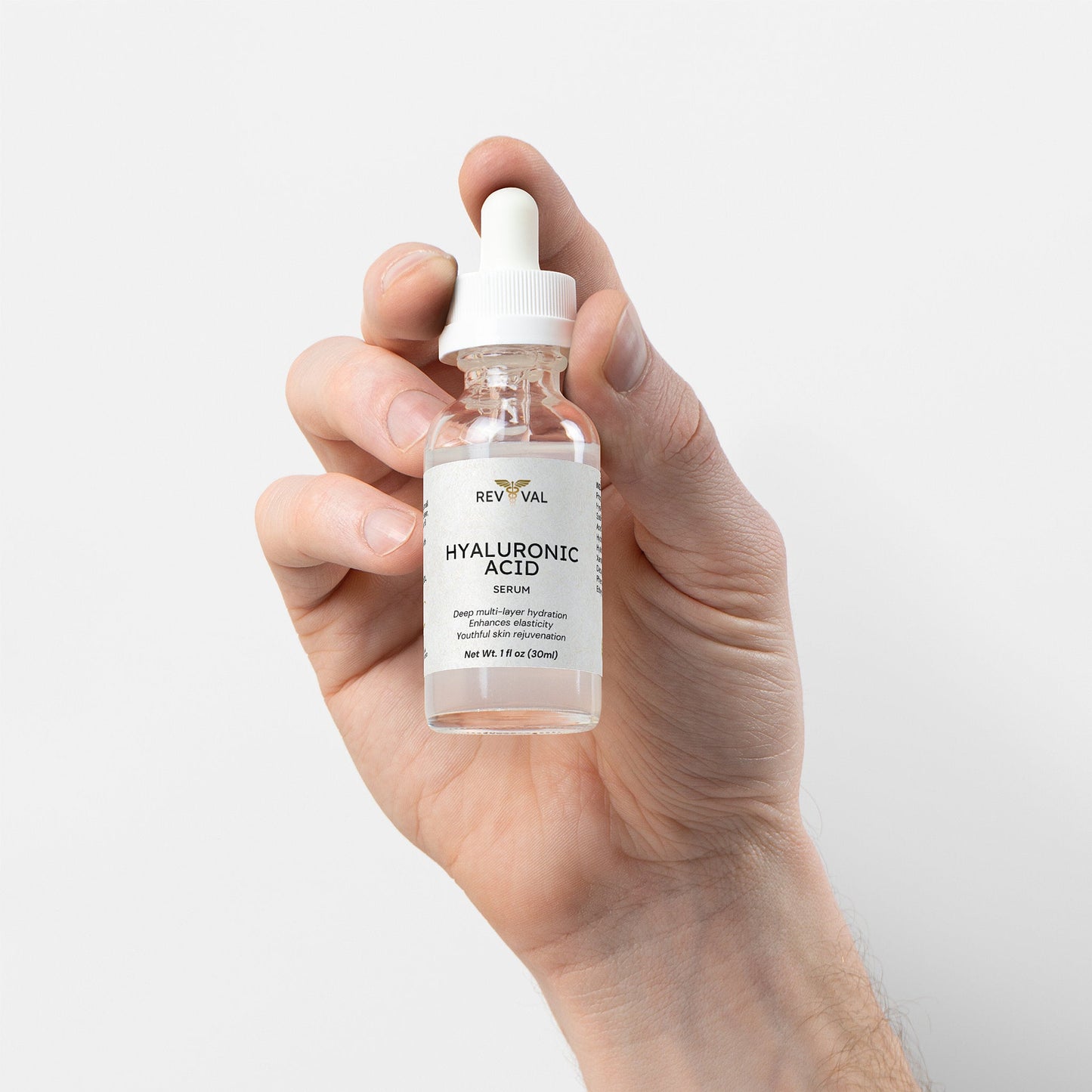 Hand holding a bottle of Reviva Labs Hyaluronic Acid Serum against a white background
