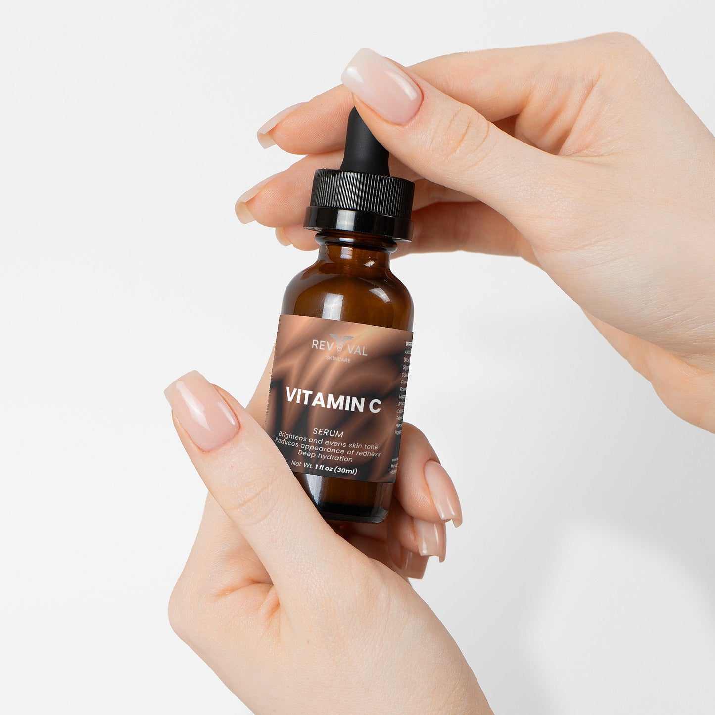 Hand holding a bottle of Reviva Labs Vitamin C Serum against a white background