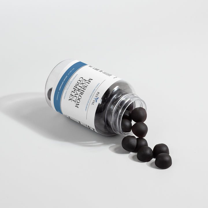 Bottle of black pills spilling out onto a light gray background