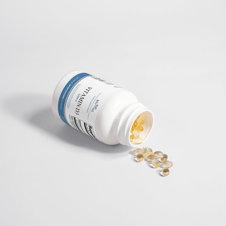 Open supplement bottle with pills spilling out on a light gray background