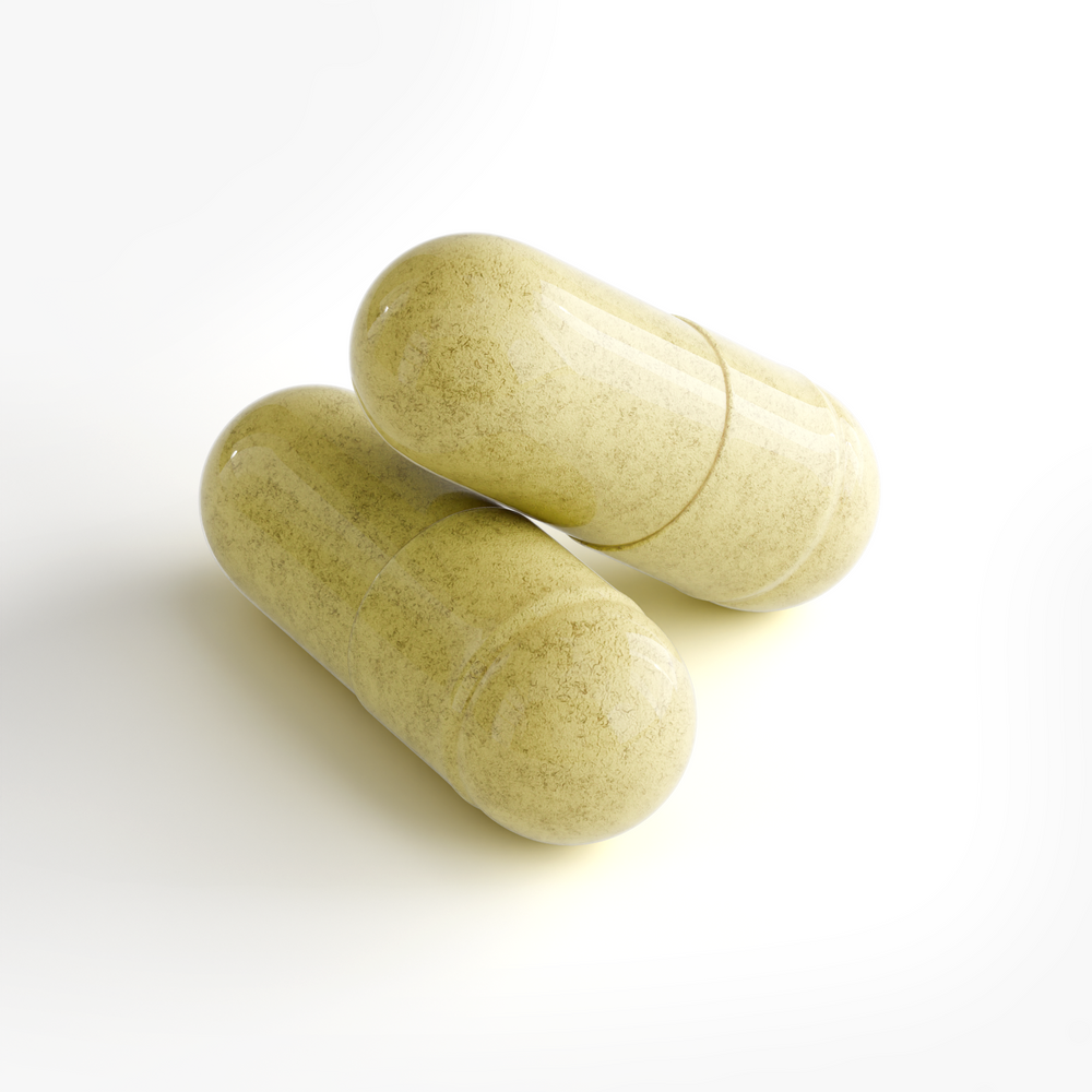 Two pale yellow-green herbal supplement capsules with a speckled texture, resting on a clean white background.