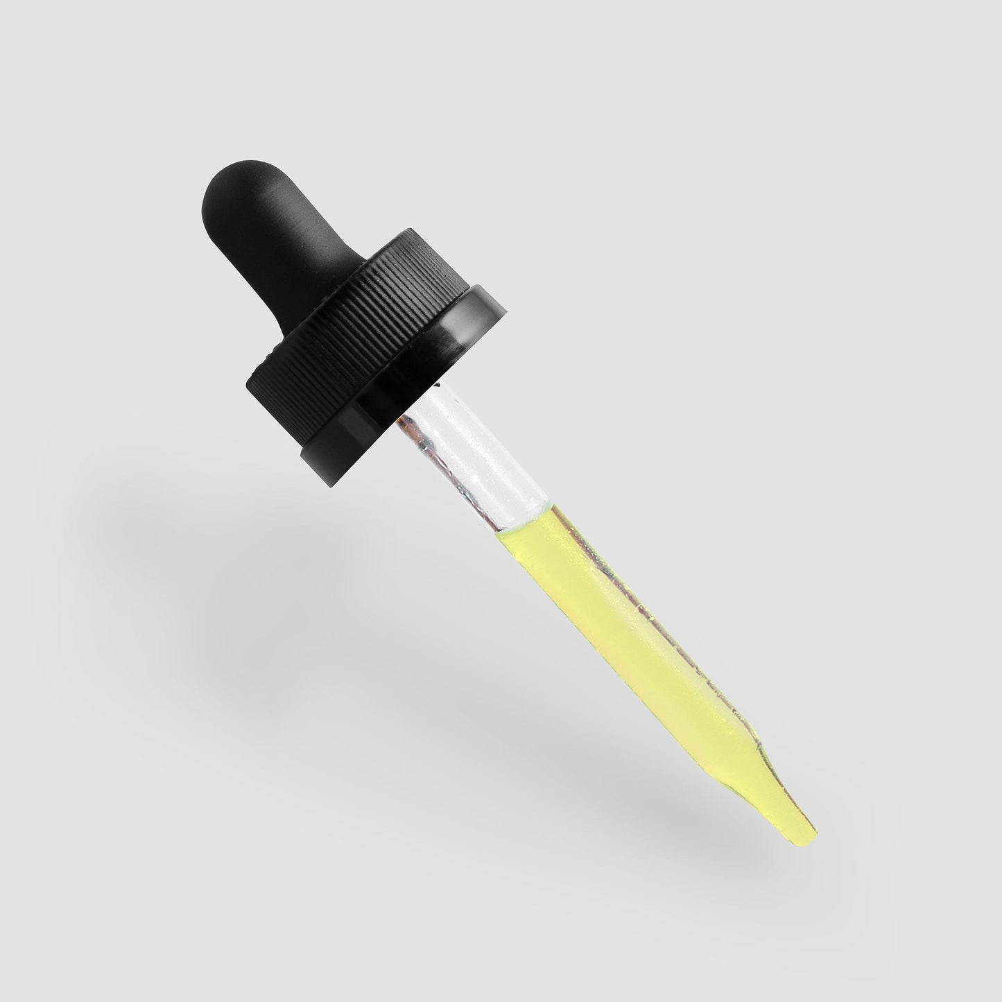 Dropper bottle with black cap and yellow liquid on a light gray background