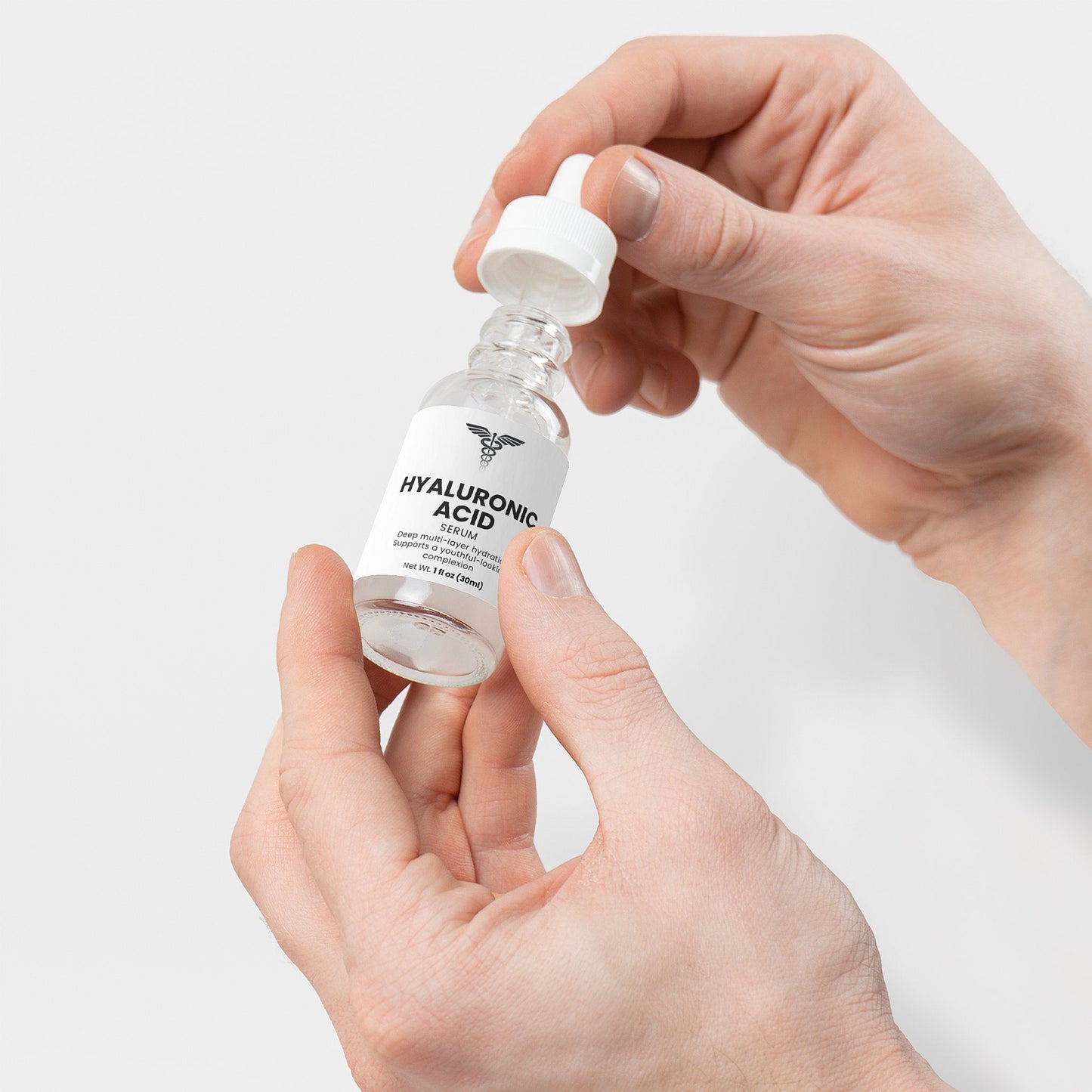 Hand holding a bottle labeled 'Hyaluronic Acid' against a light gray background