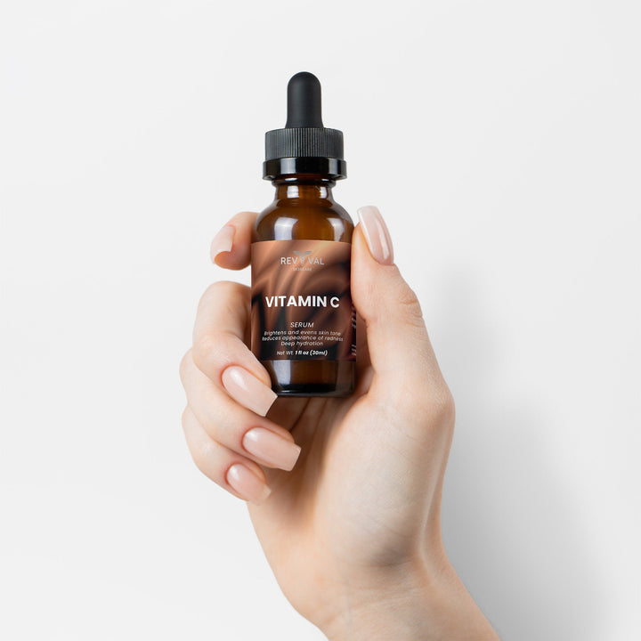Hand holding a bottle of Revival Vitamin C Serum against a white background