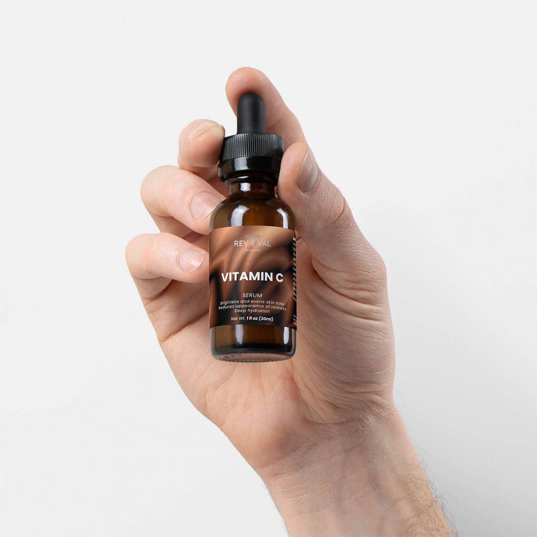Hand holding a bottle of vitamin C serum against a light background